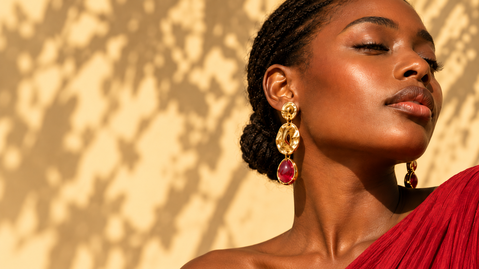 Close portrait of a woman wearing sculptural gold earrings with ruby drops